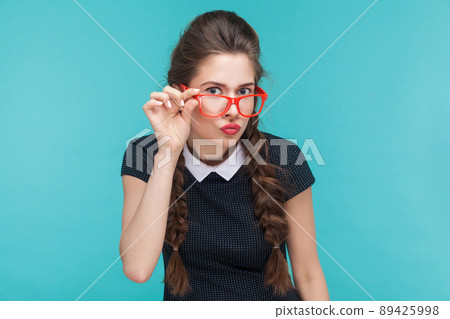 Portrait of young woman with wevy pigtails and red glasses. Studio shot Portrait of young woman with wevy pigtails and red glasses. Studio shot 89425998