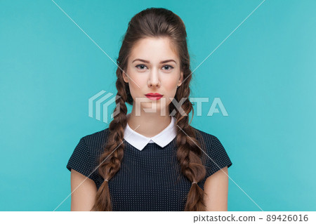 Portrait of young woman little smile at camera. Indoor, studio shot on blue background 89426016