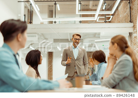 Man standing in office and explaining new ideas to colleagues Man standing in office and explaining new ideas to colleagues 89426148