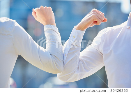 Instead of greeting with hug or handshake man and woman bump elbows on a street. Instead of greeting with hug or handshake man and woman bump elbows on a street. 89426263