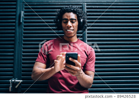 Cheerful millennial man choosing songs and connecting to bluetooth for using earphones Cheerful millennial man choosing songs and connecting to bluetooth for using earphones 89426528