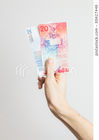 20 EUR and 20 CHF banknotes held in hand. 20 EUR and 20 CHF banknotes held in hand. 89427446