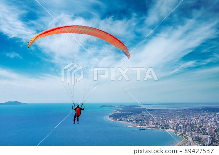 Paraglider is starting. Parachute is filling with air in the mountains alps on a sunny day in albania Paraglider is starting. Parachute is filling with air in the mountains alps on a sunny day in albania 89427537