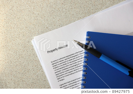 Property release blank form with blue notepad and blue pen lies on photographers table. Property release signing photo Property release blank form with blue notepad and blue pen lies on photographers table. Property release signing photo 89427975