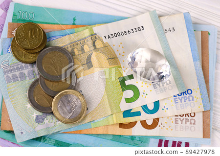 Euro money bills and coins with large diamond close up. Big amount of euro money and huge transparent gem on table. Business and jewellery Euro money bills and coins with large diamond close up. Big amount of euro money and huge transparent gem on table. Business and jewellery 89427978