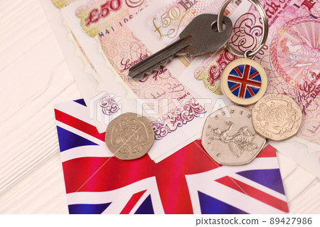 UK money bills and key for house close up. Big amount of United Kingdom pounds and silver key on table. Business and real estate concept 89427986