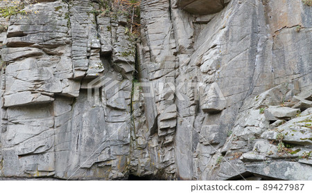 Light coarse natural rock stone background. Mining cliff rough front surface. Big limestone stack backdrop. Heavy grunge damaged granite block texture 89427987