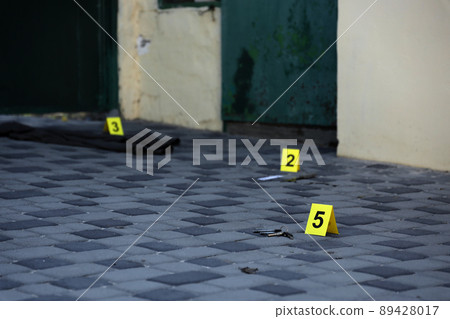Evidence with yellow CSI marker for evidence numbering on the residental backyard in evening. Crime scene investigation concept Evidence with yellow CSI marker for evidence numbering on the residental backyard in evening. Crime scene investigation concept 89428017
