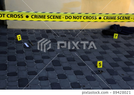 Crime scene tape for covering the area cordon. Yellow tape with blurred forensic law enforcement background in cinematic tone Crime scene tape for covering the area cordon. Yellow tape with blurred forensic law enforcement background in cinematic tone 89428021