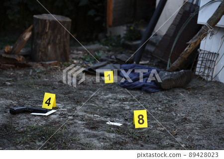 Evidence with yellow CSI marker for evidence numbering on the residental backyard in evening. Crime scene investigation concept Evidence with yellow CSI marker for evidence numbering on the residental backyard in evening. Crime scene investigation concept 89428023