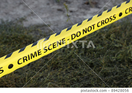 Crime scene tape for covering the area cordon. Yellow tape with blurred forensic law enforcement background in cinematic tone Crime scene tape for covering the area cordon. Yellow tape with blurred forensic law enforcement background in cinematic tone 89428056