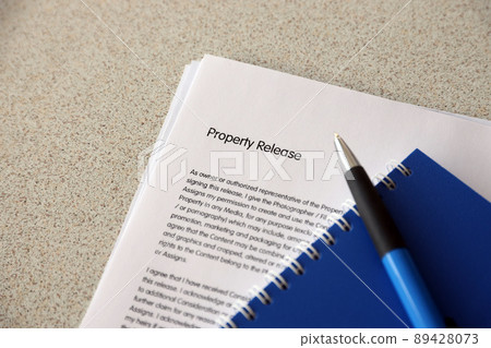 Property release blank form with blue notepad and blue pen lies on photographers table. Property release signing photo Property release blank form with blue notepad and blue pen lies on photographers table. Property release signing photo 89428073