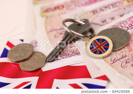 UK money bills and key for house close up. Big amount of United Kingdom pounds and silver key on table. Business and real estate concept 89428086