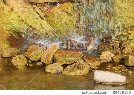 Waterfall among stones and trees. Close-up of boulders in water. Huge stones in green moss. Beautiful landscape of fast waterfall with small whirlpools Waterfall among stones and trees. Close-up of boulders in water. Huge stones in green moss. Beautiful landscape of fast waterfall with small whirlpools 89428109