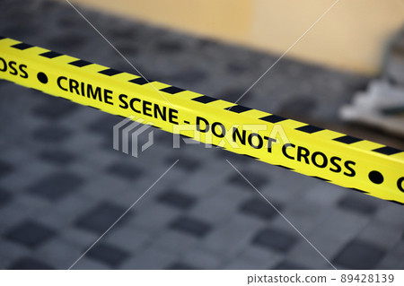 Crime scene tape for covering the area cordon. Yellow tape with blurred forensic law enforcement background in cinematic tone 89428139