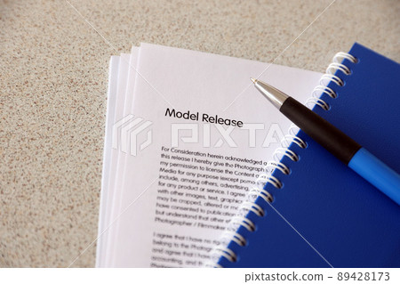 Model release blank form with blue notepad and blue pen lies on photographers table. Model release signing photo Model release blank form with blue notepad and blue pen lies on photographers table. Model release signing photo 89428173