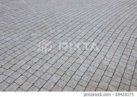 Gray color paving slabs in the pedestrian street sidewalk. Rough cobblestone pattern with many square shaped stones Gray color paving slabs in the pedestrian street sidewalk. Rough cobblestone pattern with many square shaped stones 89428175