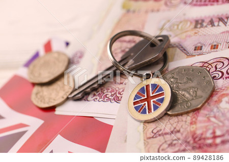 UK money bills and key for house close up. Big amount of United Kingdom pounds and silver key on table. Business and real estate concept UK money bills and key for house close up. Big amount of United Kingdom pounds and silver key on table. Business and real estate concept 89428186