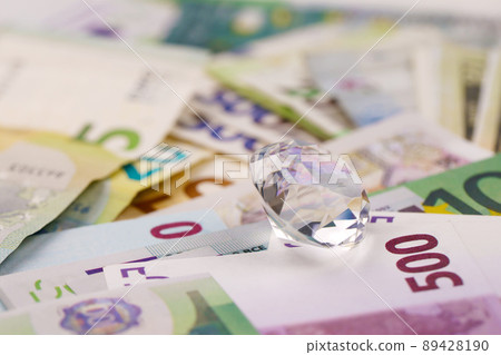 Euro and dollar money bills and coins with large diamond close up. Big amount of money and huge transparent gem on table. Business and jewellery Euro and dollar money bills and coins with large diamond close up. Big amount of money and huge transparent gem on table. Business and jewellery 89428190