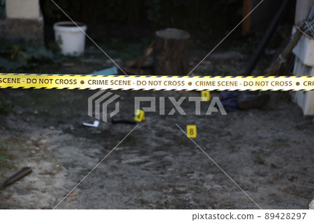 Crime scene tape for covering the area cordon. Yellow tape with blurred forensic law enforcement background in cinematic tone 89428297