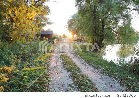 Beautiful autumn landscape with sunset among the green and orange trees. Picturesque place with lake 89428309