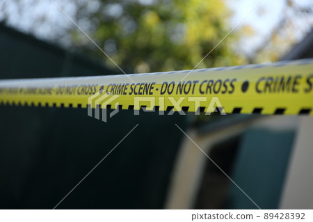 Crime scene tape for covering the area cordon. Yellow tape with blurred forensic law enforcement background in cinematic tone 89428392