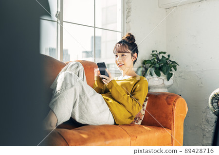 在沙發上的女人看智能手機 89428716