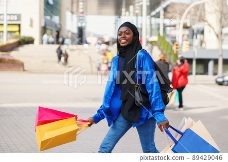 Glad Muslim shopper walking in modern city Glad Muslim shopper walking in modern city 89429046