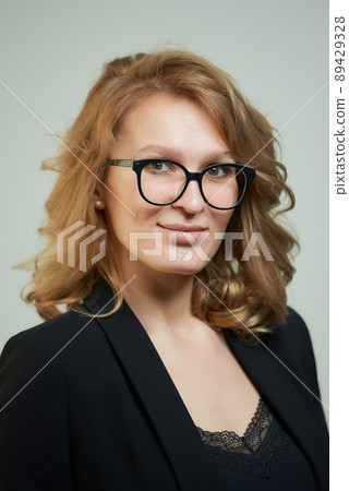 A stylish young woman in glasses dressed in a black suit with a black shirt. A stylish young woman in glasses dressed in a black suit with a black shirt. 89429328