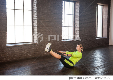 Strong woman doing boat exercise. Indoor shot Strong woman doing boat exercise. Indoor shot 89429699