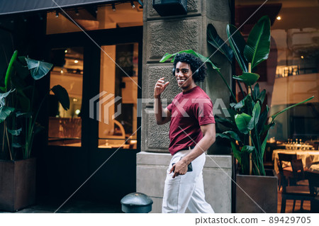 Joyful hipster guy in bluetooth headphones smiling at camer 89429705