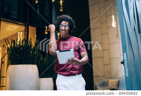 Excited man in spectacles using digital tablet for reading great web news in social media Excited man in spectacles using digital tablet for reading great web news in social media 89430692