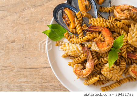 stir-fried spiral pasta with seafood and basil sauce 89431782