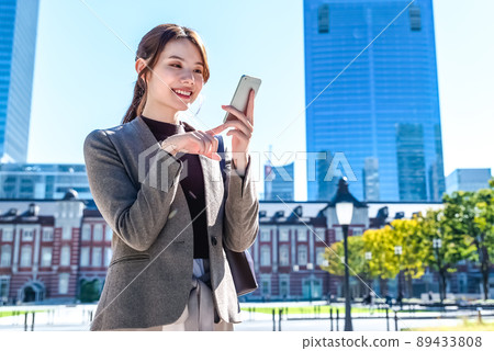 A young business woman operating a smartphone in Tokyo Marunouchi A young business woman operating a smartphone in Tokyo Marunouchi 89433808