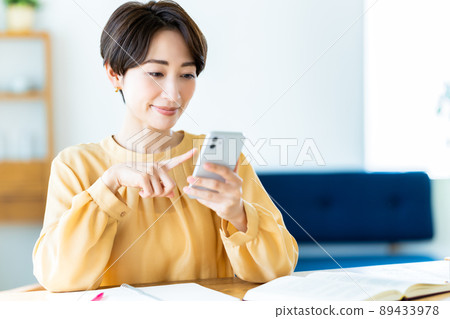 在家學習時使用智能手機的中年婦女 在家學習時使用智能手機的中年婦女 89433978