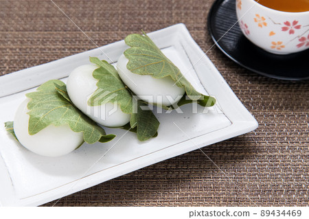 Three Kashiwamochi and Hojicha lined up on a white plate 89434469