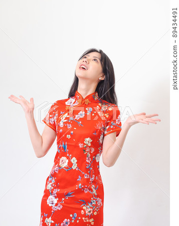 Portrait of young asian woman wearing traditional cheongsam qipao dress over isolated white background holding copyspace with two hands. Portrait of young asian woman wearing traditional cheongsam qipao dress over isolated white background holding copyspace with two hands. 89434491