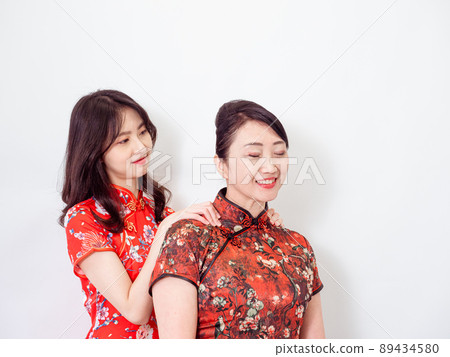 Portrait of Asian Young daughter giving her mother a massage for Relieve stress on white background(both wearing traditional cheongsam qipao dress). Portrait of Asian Young daughter giving her mother a massage for Relieve stress on white background(both wearing traditional cheongsam qipao dress). 89434580