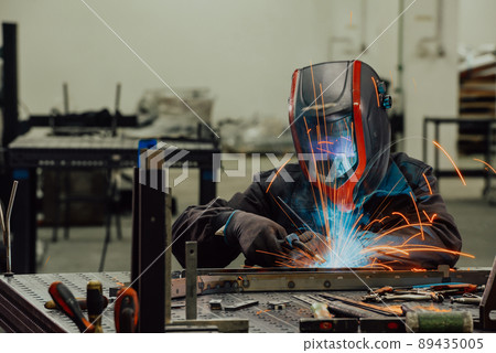 Professional Heavy Industry Welder Working Inside factory, Wears Helmet and Starts Welding. Selective Focus Professional Heavy Industry Welder Working Inside factory, Wears Helmet and Starts Welding. Selective Focus 89435005