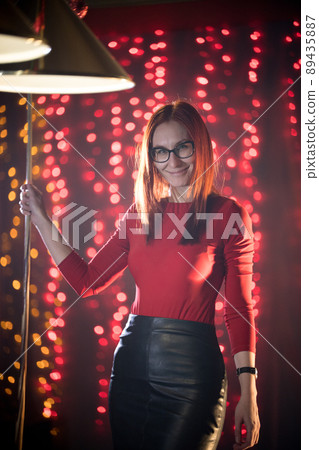 A smiling ginger woman in black skirt playing billiard. Standing holding a cue 89435887