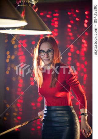 A ginger woman in black skirt playing billiard A ginger woman in black skirt playing billiard 89435890
