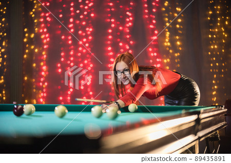 Smiling ginger woman playing billiard in nice architected club 89435891
