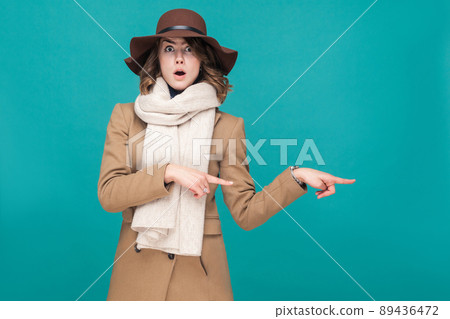 Amazement woman pointing finger at copy space with shocked face. Studio shot 89436472