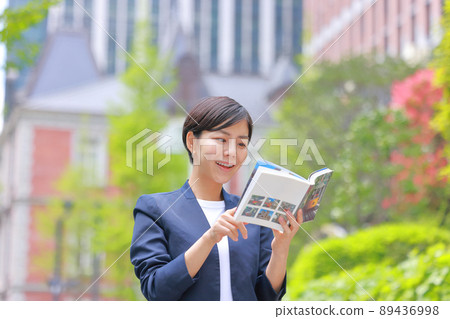 A smiling woman who spreads the guidebook 2 89436998