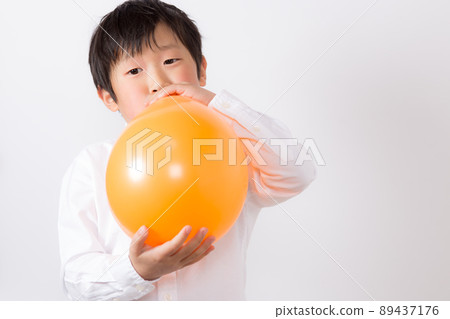 Boy inflating a balloon Boy inflating a balloon 89437176