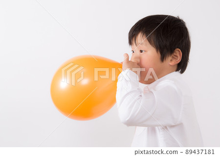 Boy inflating a balloon Boy inflating a balloon 89437181