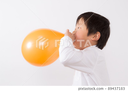 Boy inflating a balloon Boy inflating a balloon 89437183