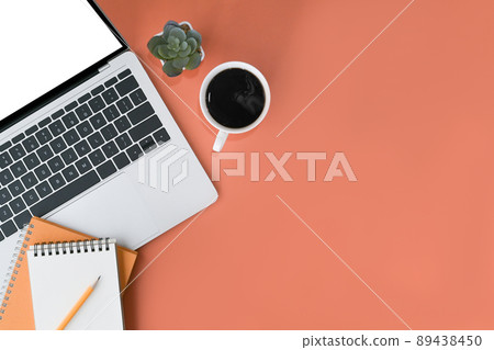 Computer laptop, notepad and coffee cup on orange background. Flat lay, Top view with copy space. 89438450