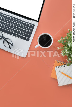 Mock up laptop with white display, coffee cup and notebook on orange background. Flay lay. 89438451