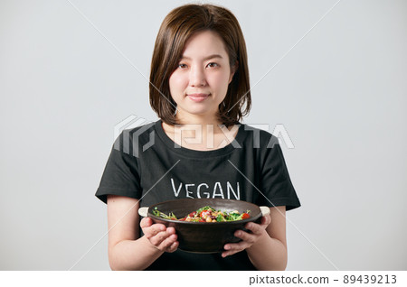 年輕的素食女性端著沙拉碗微笑 89439213